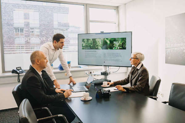 Steuerberatungsgespräch mit Präsentation von Auswertungen auf großem Monitor
